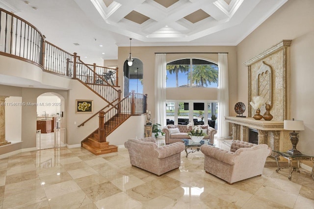 living room with coffered ceiling, stairway, crown molding, baseboards, and a towering ceiling