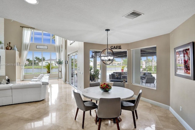 dining area with a wealth of natural light, visible vents, baseboards, and a textured ceiling