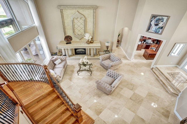 interior space featuring stairway, baseboards, arched walkways, and a towering ceiling