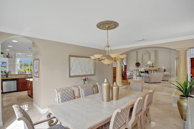 dining room featuring crown molding, baseboards, a chandelier, decorative columns, and arched walkways