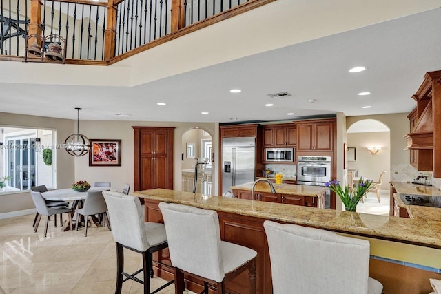 kitchen with stainless steel appliances, arched walkways, a breakfast bar area, and decorative backsplash