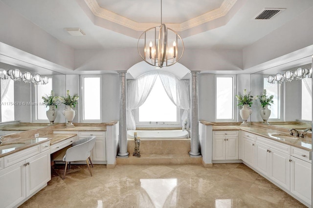 bathroom with visible vents, a garden tub, a tray ceiling, ornate columns, and a sink