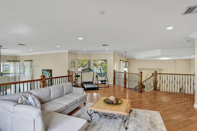 living room with recessed lighting, visible vents, light wood-style flooring, and ornamental molding