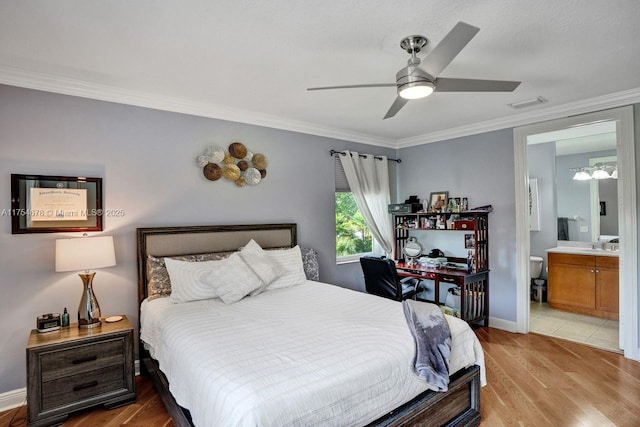 bedroom with visible vents, ensuite bath, light wood-style floors, crown molding, and baseboards