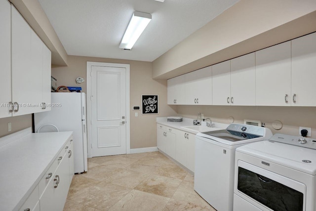 clothes washing area featuring baseboards, washing machine and dryer, cabinet space, a textured ceiling, and a sink