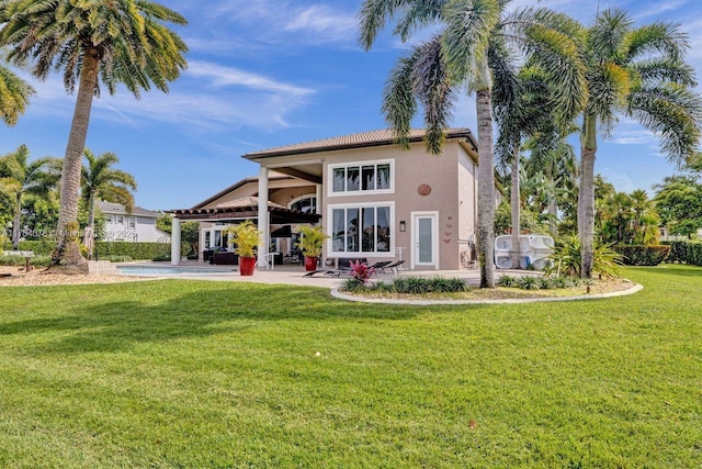 rear view of property with stucco siding, a yard, and a patio area