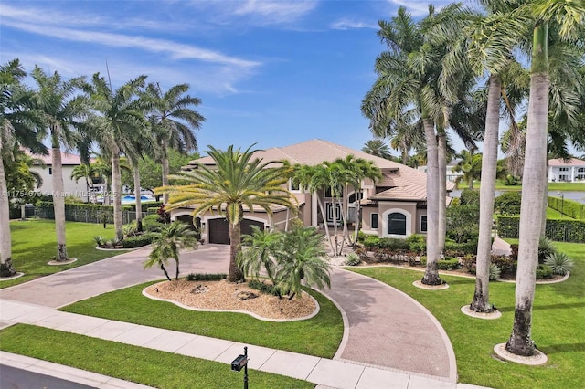 mediterranean / spanish house with a front lawn, a tiled roof, driveway, and stucco siding