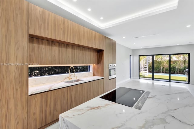 kitchen featuring light stone counters, marble finish floor, modern cabinets, black electric cooktop, and a sink