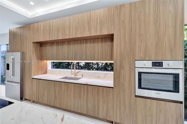 kitchen featuring oven, modern cabinets, and freestanding refrigerator