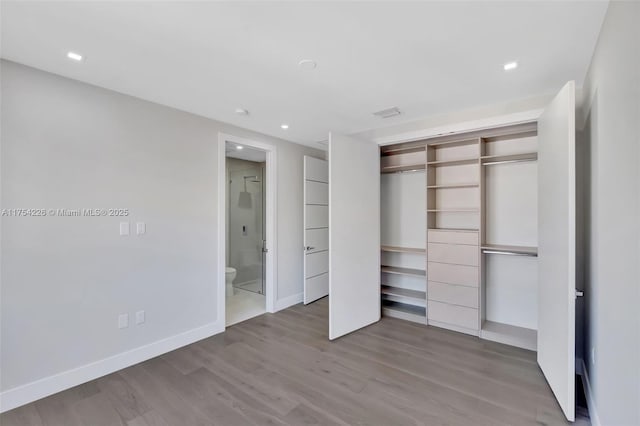 unfurnished bedroom featuring wood finished floors, baseboards, recessed lighting, a closet, and ensuite bathroom