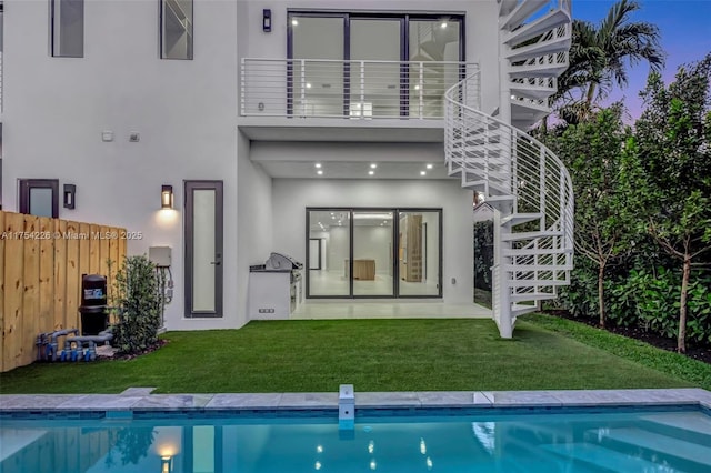 back of property with a fenced in pool, stairway, stucco siding, a balcony, and a yard