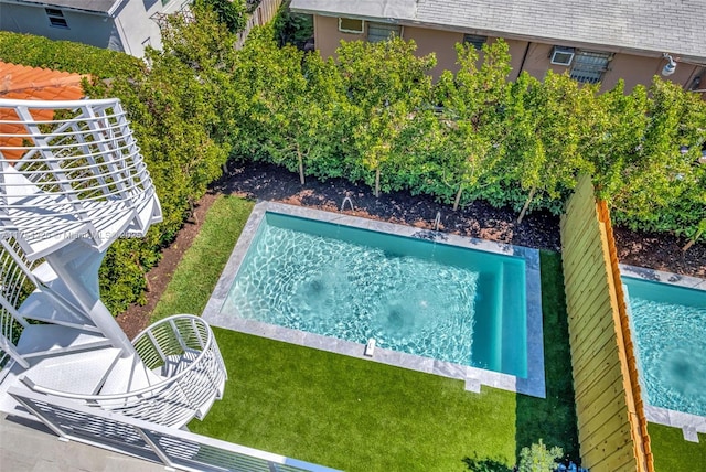 view of swimming pool featuring a lawn, a jacuzzi, and a fenced backyard