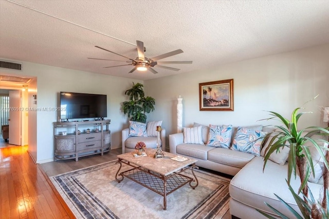 living area with a ceiling fan, visible vents, light wood finished floors, and a textured ceiling