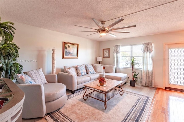 living area with a textured ceiling, a ceiling fan, and light wood finished floors