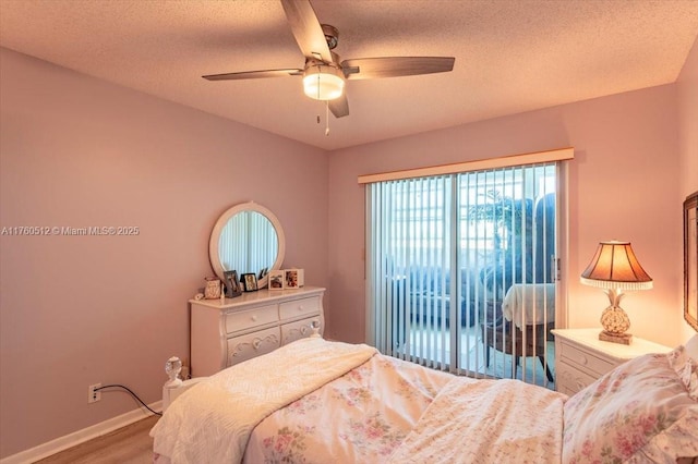 bedroom with ceiling fan, baseboards, wood finished floors, a textured ceiling, and access to outside