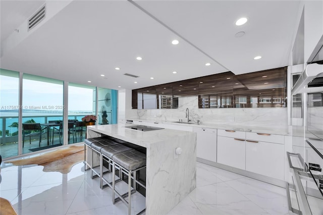 kitchen featuring light stone countertops, visible vents, white cabinetry, modern cabinets, and tasteful backsplash