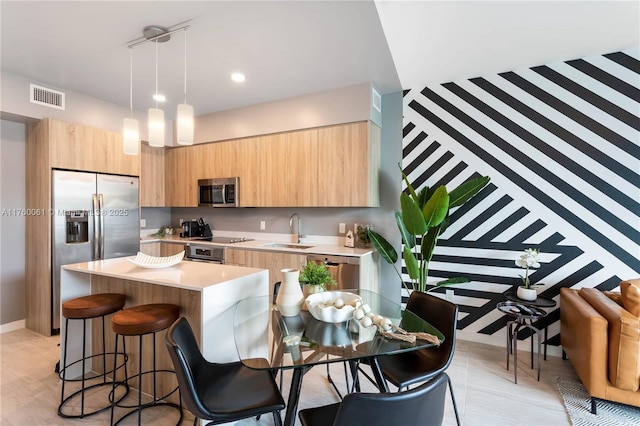 kitchen with light brown cabinets, visible vents, appliances with stainless steel finishes, and a sink