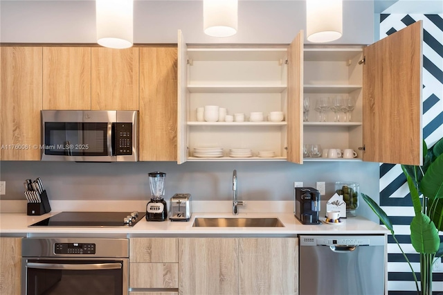 kitchen featuring modern cabinets, light brown cabinetry, a sink, appliances with stainless steel finishes, and light countertops