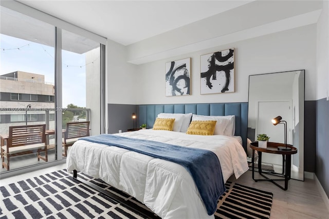 bedroom with a wall of windows, baseboards, wood finished floors, and access to outside