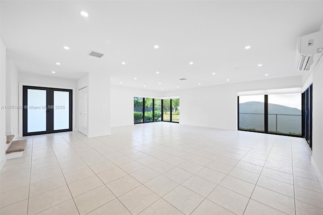 empty room featuring an AC wall unit, recessed lighting, french doors, light tile patterned flooring, and visible vents