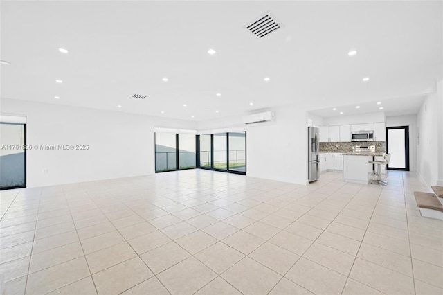 unfurnished living room with light tile patterned floors, visible vents, recessed lighting, and a wall mounted air conditioner