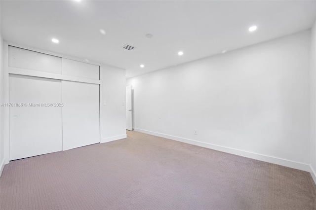 unfurnished bedroom with recessed lighting, visible vents, light carpet, and a closet