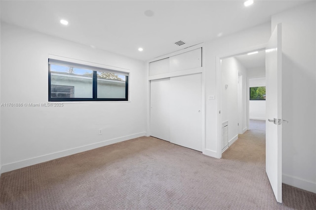 unfurnished bedroom featuring recessed lighting, visible vents, light colored carpet, and multiple windows