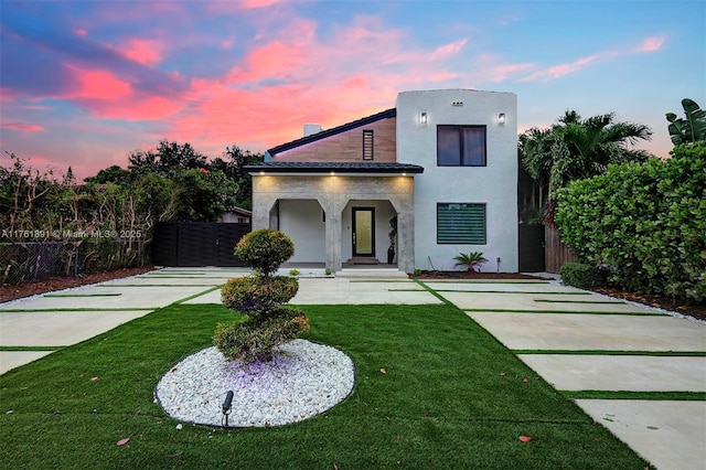 view of front of property featuring stucco siding, a front yard, and fence