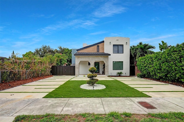 view of front of house featuring stucco siding, a front lawn, and fence