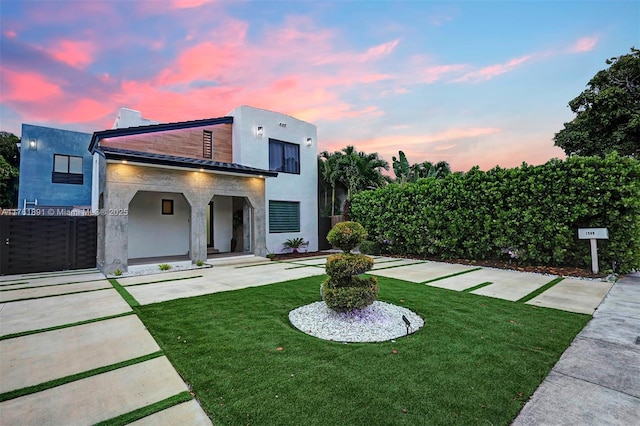 back of property featuring stucco siding, driveway, and a lawn