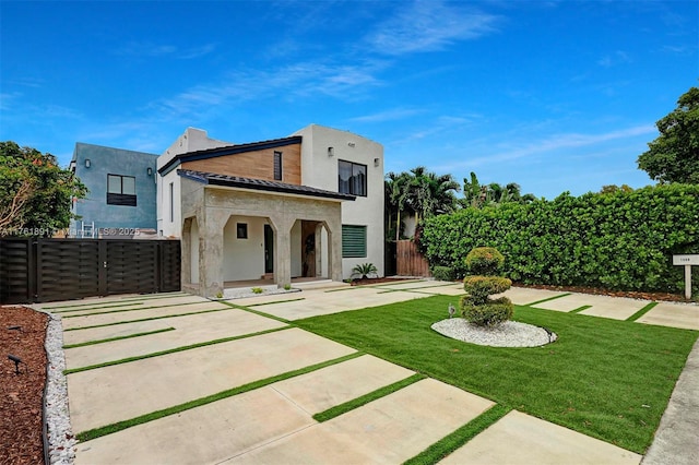 back of house with a gate, stucco siding, a lawn, and fence