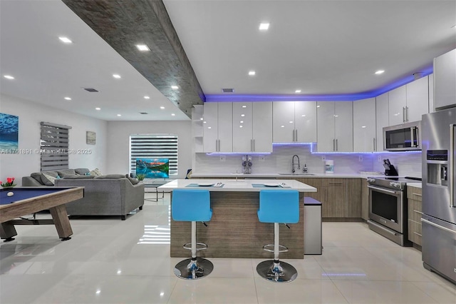 kitchen with a breakfast bar, stainless steel appliances, modern cabinets, and a sink