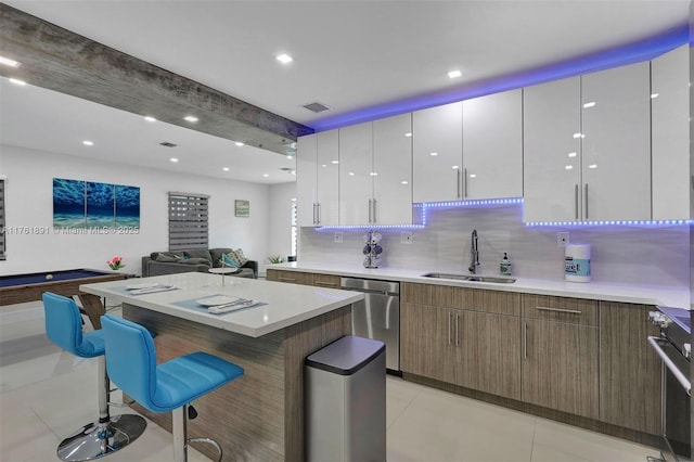 kitchen featuring visible vents, a sink, a kitchen breakfast bar, range, and dishwasher