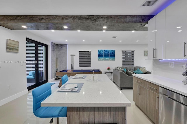 kitchen with visible vents, modern cabinets, stainless steel dishwasher, open floor plan, and light stone countertops