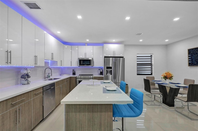 kitchen with a breakfast bar area, visible vents, light tile patterned flooring, a sink, and appliances with stainless steel finishes