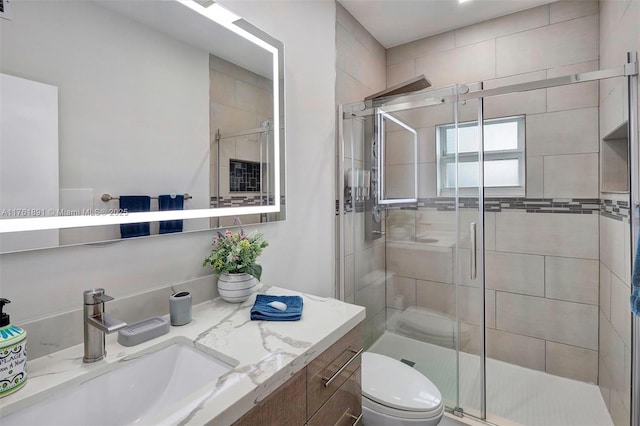 bathroom with vanity, a shower stall, and toilet