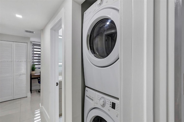 laundry room with light tile patterned floors, visible vents, laundry area, and stacked washing maching and dryer