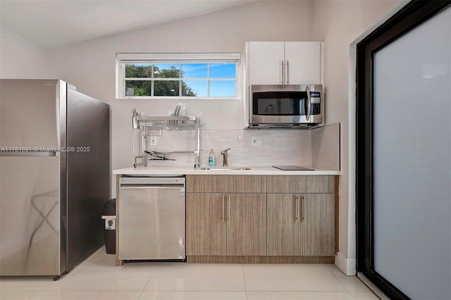 kitchen featuring vaulted ceiling, stainless steel appliances, light countertops, and a sink