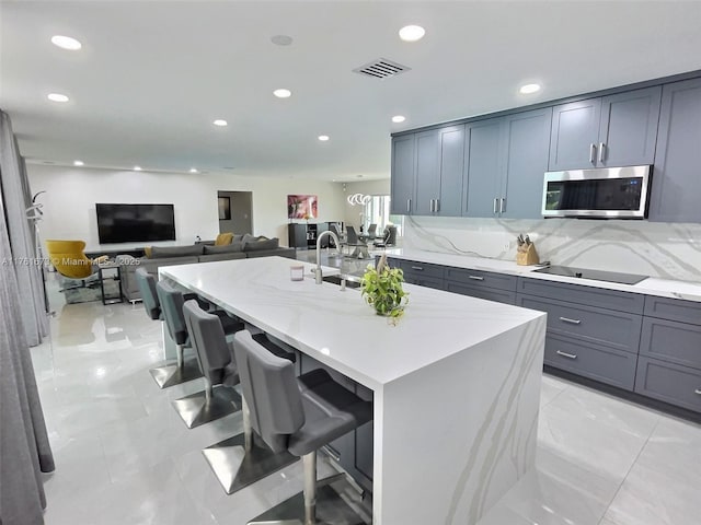 kitchen featuring stainless steel microwave, tasteful backsplash, recessed lighting, a breakfast bar area, and light stone countertops