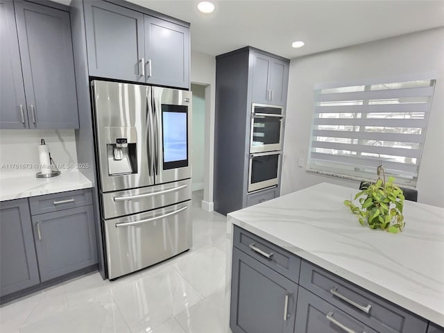 kitchen featuring light stone counters, gray cabinetry, recessed lighting, and stainless steel appliances