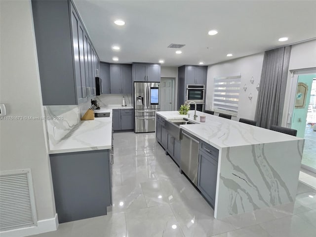 kitchen with visible vents, gray cabinets, appliances with stainless steel finishes, and a sink