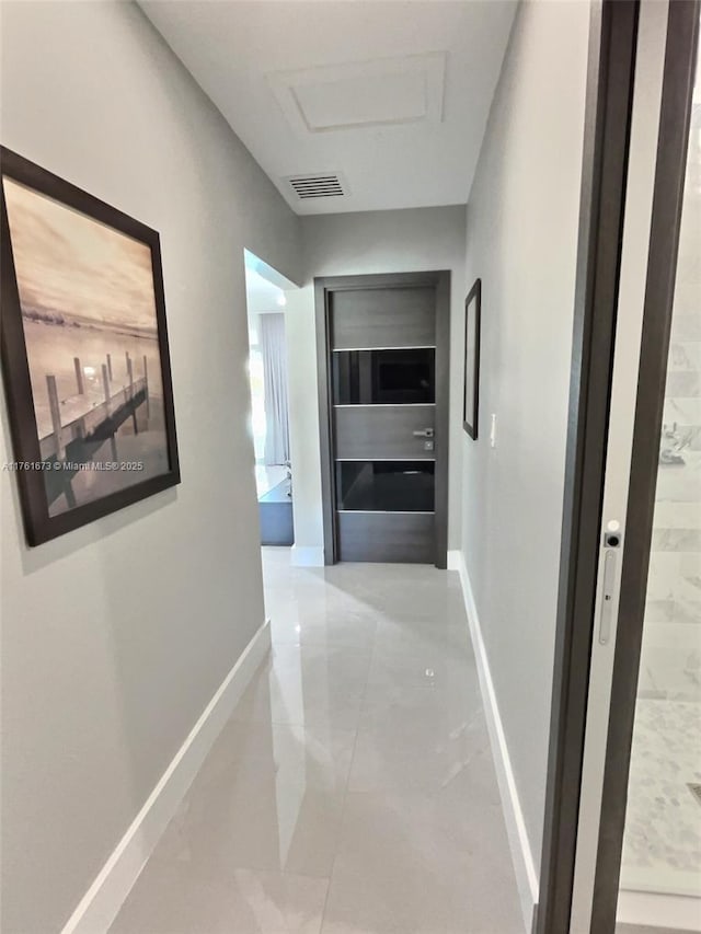 hallway featuring visible vents, baseboards, marble finish floor, and attic access