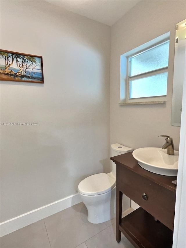 half bathroom featuring tile patterned floors, toilet, vanity, and baseboards