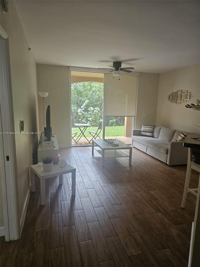 unfurnished living room with floor to ceiling windows, a ceiling fan, dark wood-style flooring, and baseboards