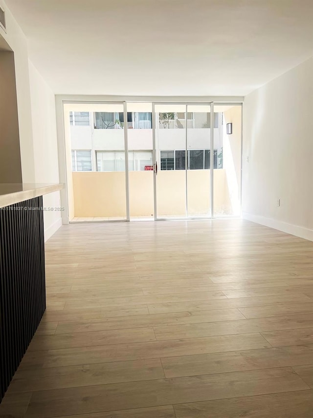 spare room featuring light wood-style flooring, visible vents, and a wealth of natural light