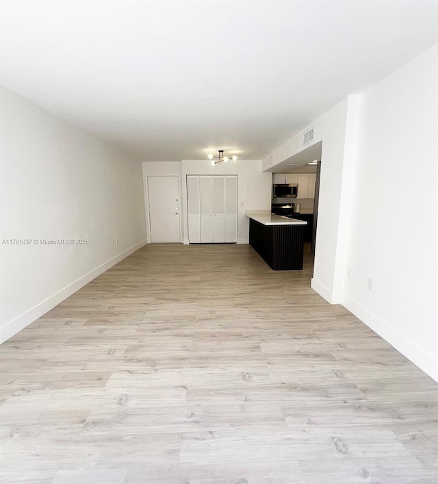 unfurnished living room featuring visible vents, light wood-style flooring, and baseboards