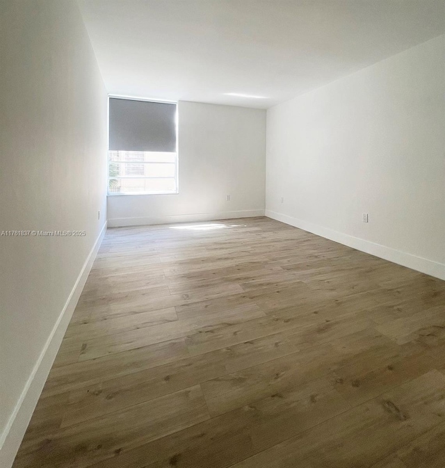 empty room with baseboards and wood finished floors