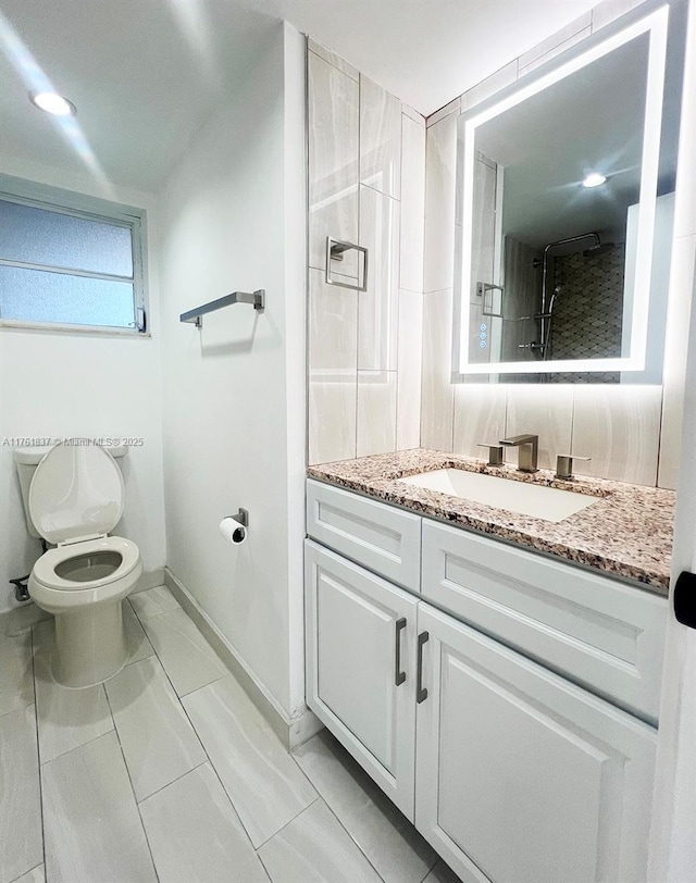 bathroom featuring baseboards, toilet, and vanity