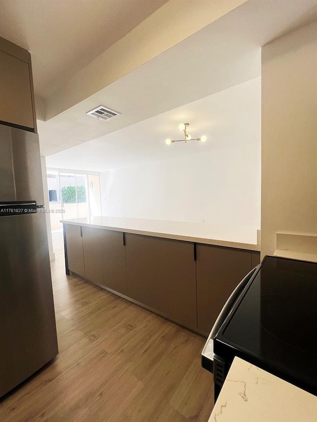 kitchen featuring visible vents, electric range, light wood-style flooring, gray cabinets, and freestanding refrigerator