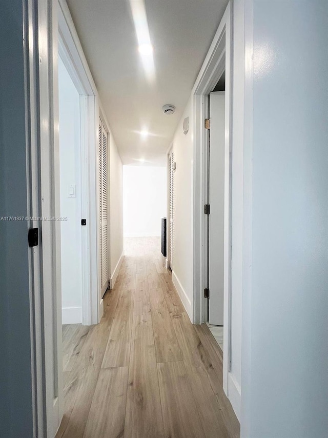 hallway featuring light wood-type flooring and baseboards